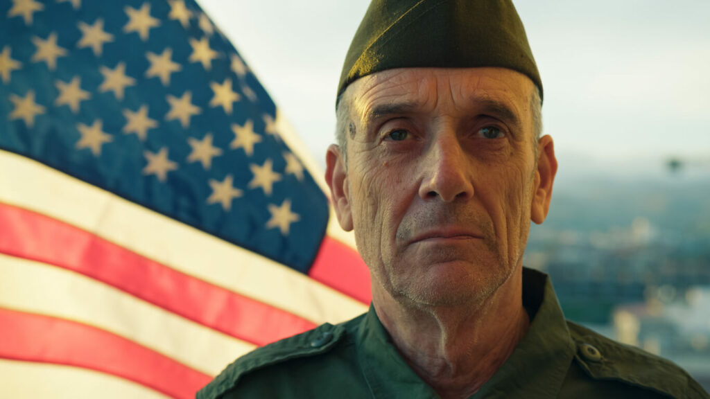 A veteran stands beside The American Flag.