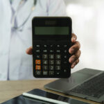 A medical practitioner holding a calculator to illustrate medical expenses and the concept of cancer funds.