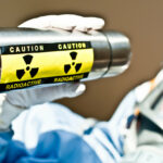 Radiation R&D Scientist Examines Blue Radioactive Liquid Substance in Beaker.