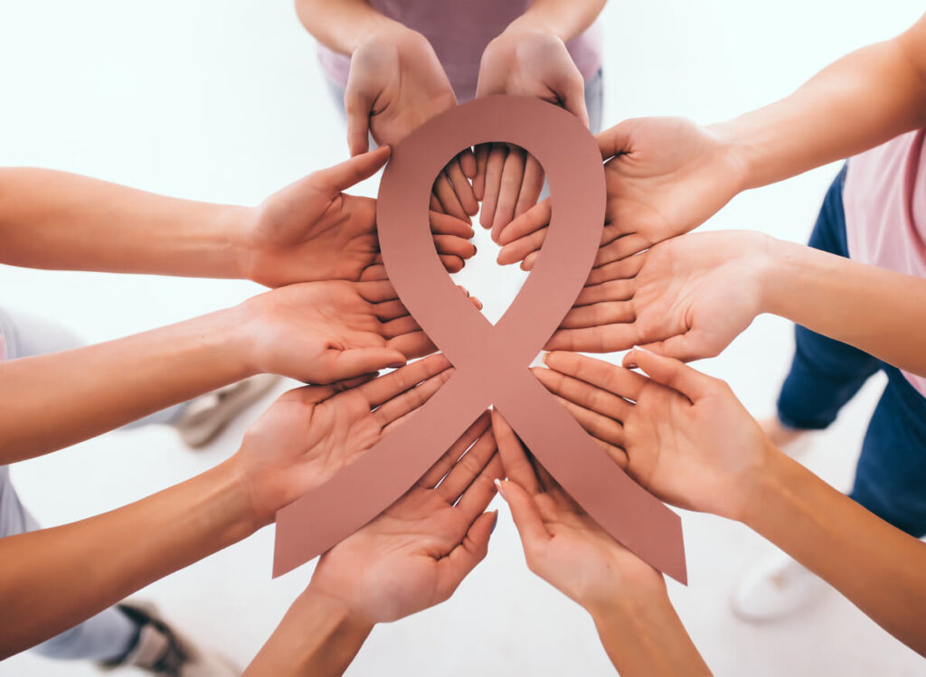 Ribbon and group of hands symbolizing Cancer Help Organizations.