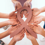 Ribbon and group of hands symbolizing Cancer Help Organizations.
